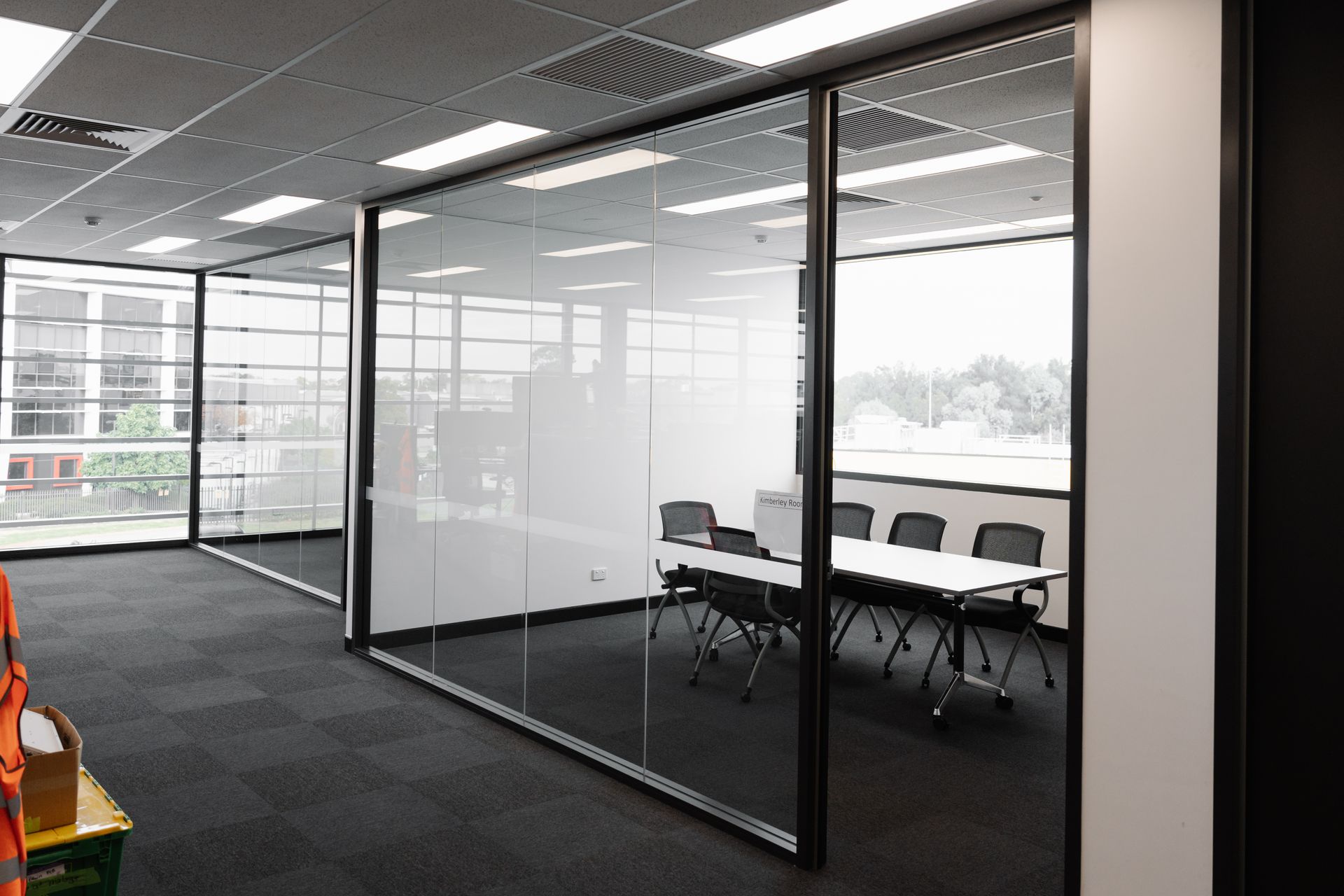 Glass-walled office room with a conference table, chairs, and natural light.