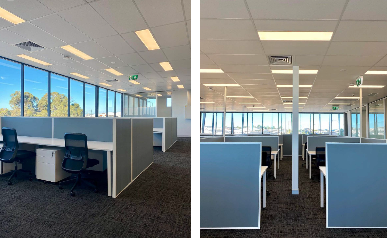 Two office spaces with cubicles and large windows, dark carpet, white walls and ceiling.