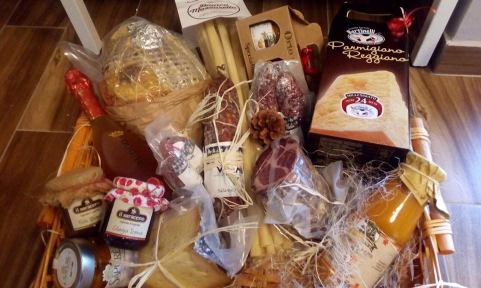 Cesto di prodotti gourmet ricco di formaggi, salumi, marmellate, grissini e miele.