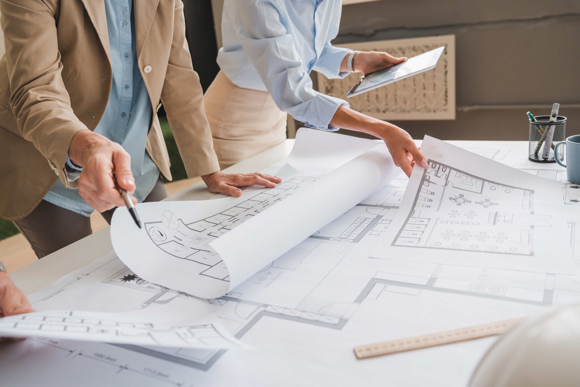 People reviewing architectural blueprints spread across a table in a bright office