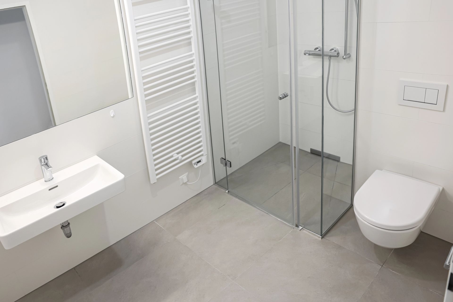 Bagno moderno, bianco, con doccia, WC e lavandino; pavimento grigio chiaro.