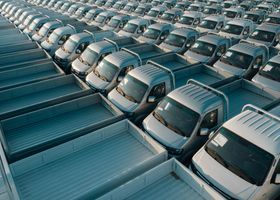 Filas de camionetas plateadas estacionadas muy juntas en un lote, vistas desde arriba.
