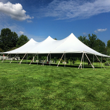 Large white event tent on a green lawn under a blue sky
