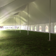 Large white event tent with arched windows and grassy floor, viewed from inside.