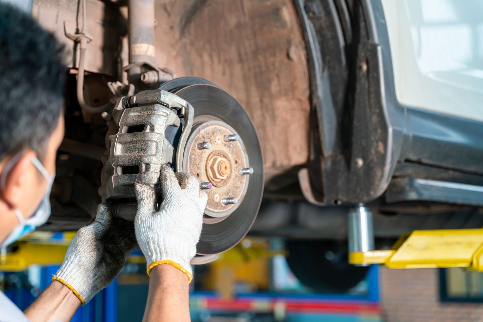 Mechanic performing brake pad fitting on car wheel assembly using wrench in auto repair shop. Mechanic performing brake pad fitting on car wheel assembly using wrench in auto repair shop.
