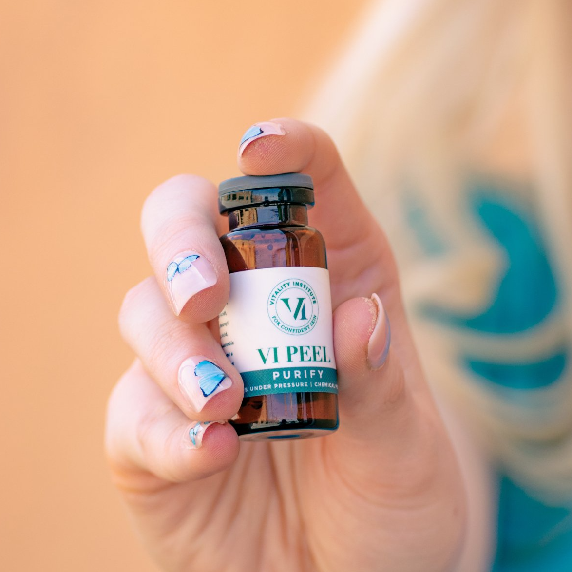 A woman is holding a bottle of vipeel in her hand.