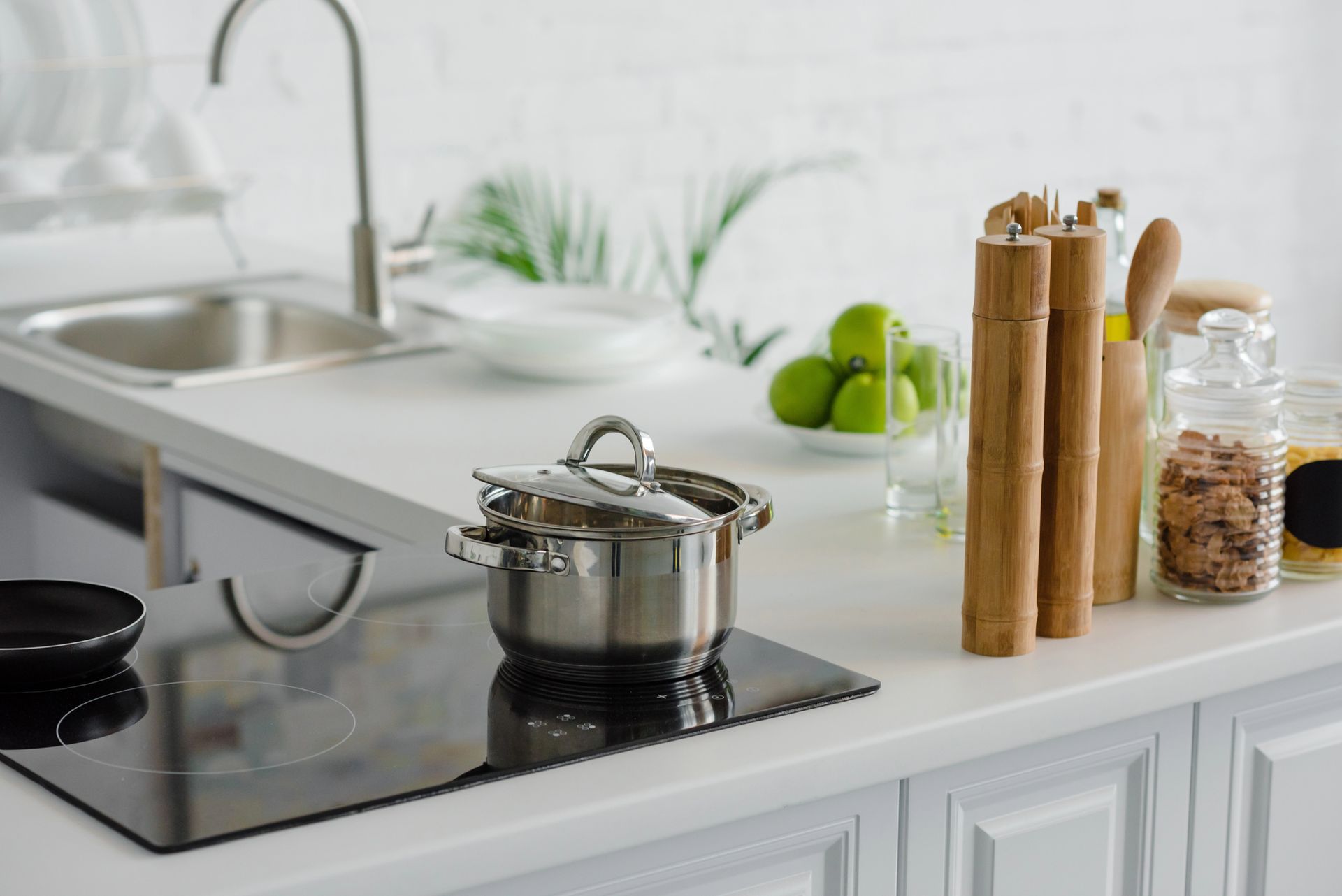 Encimera de cocina moderna con placa de cocción, olla de acero inoxidable, frutero y molinillos de especias de madera