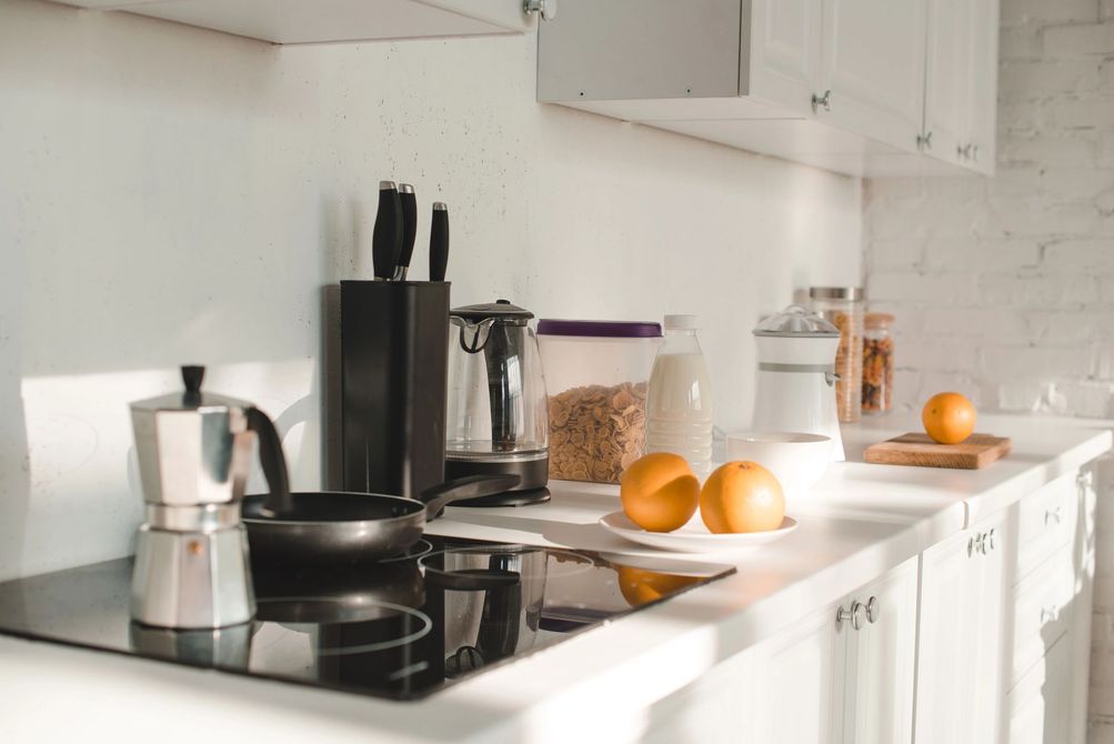 Encimera de cocina moderna y luminosa con cafetera, fruta, naranjas y tarros de cristal
