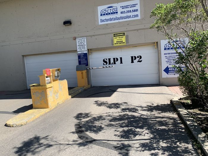Garage door labeled “SLP1 P2” with yellow concrete barriers and signs outside a building
