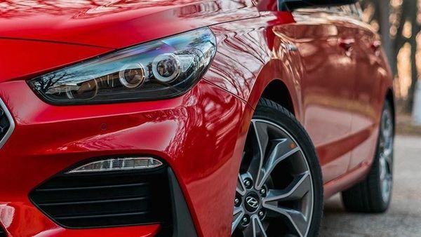 Close-up of a red sports car’s front headlight and wheel parked on a street