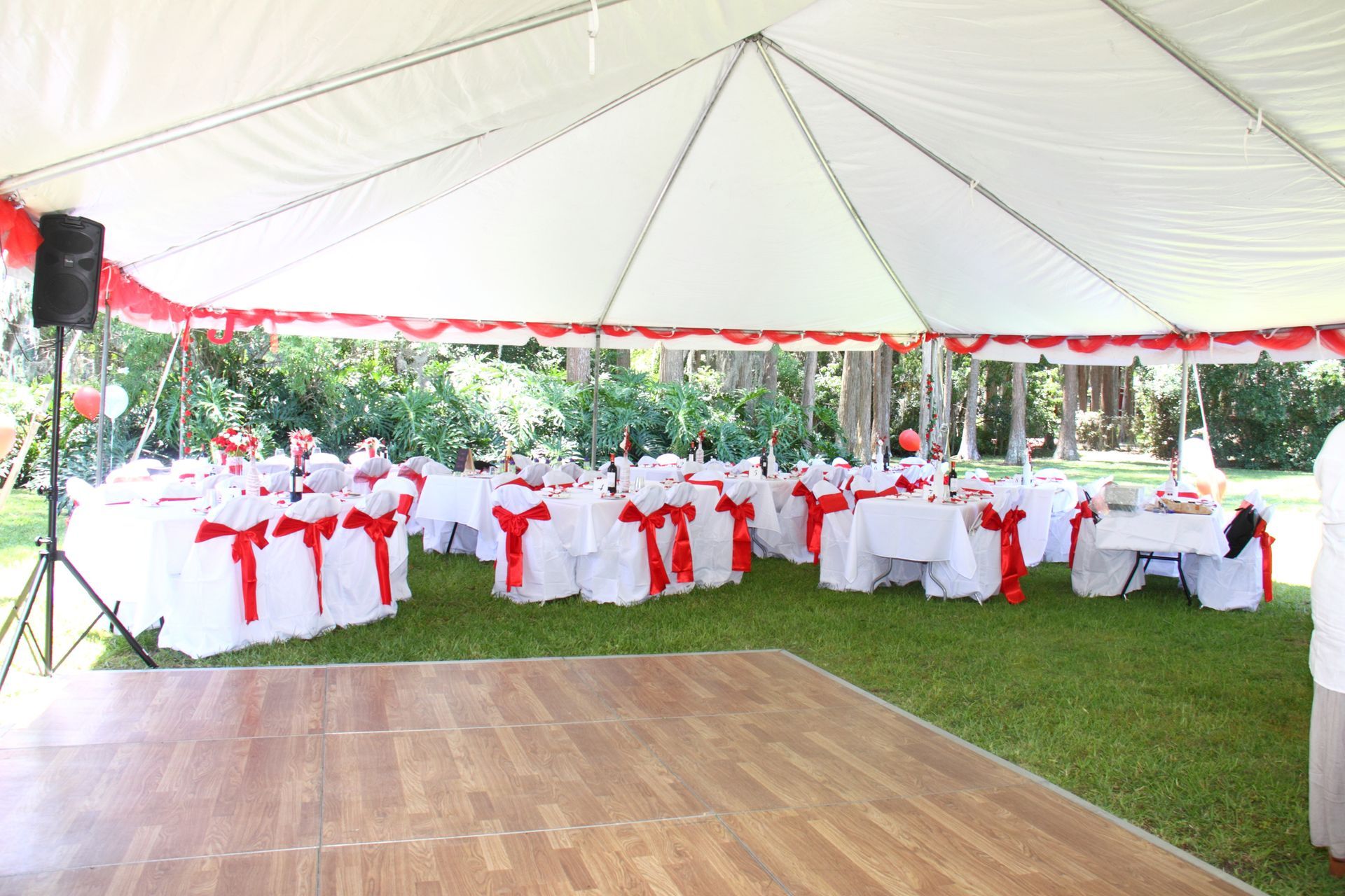A dance floor under a tent with tables and chairs set up