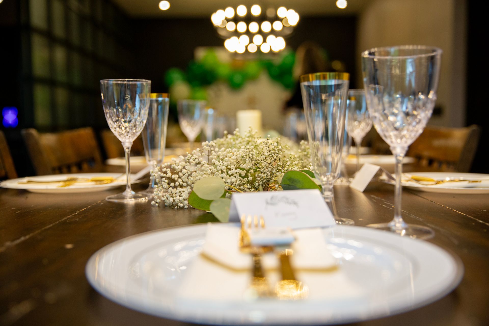A table set for a wedding reception with plates , wine glasses , and flowers.