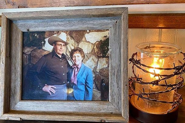 A framed photo of a couple in a rustic setting sits next to a lamp wrapped in decorative barbed wire.
