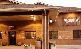 The Western Inn exterior featuring a wooden-paneled facade, a covered entrance, and decorative potted plants.