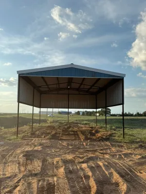 Open-sided metal shed on a dirt field under a cloudy sky at sunset