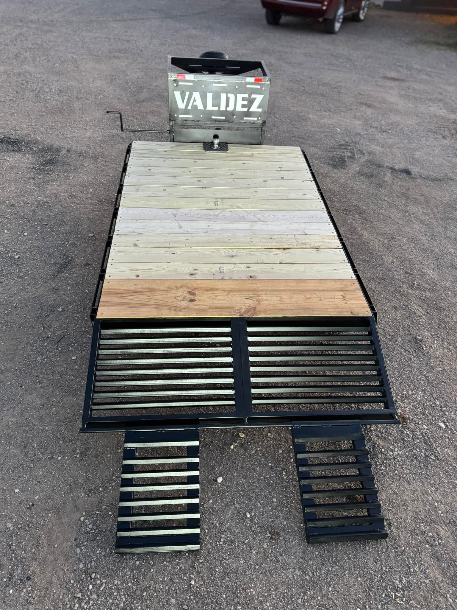 Wooden pallet-style display on pavement with a Valdez sign at the top and black grates at the bottom.