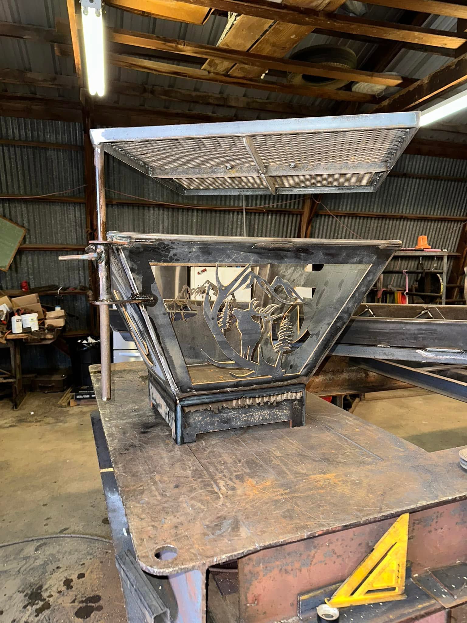 Large metal industrial hopper or mixer in a workshop, with slanted top and worn rusted surfaces
