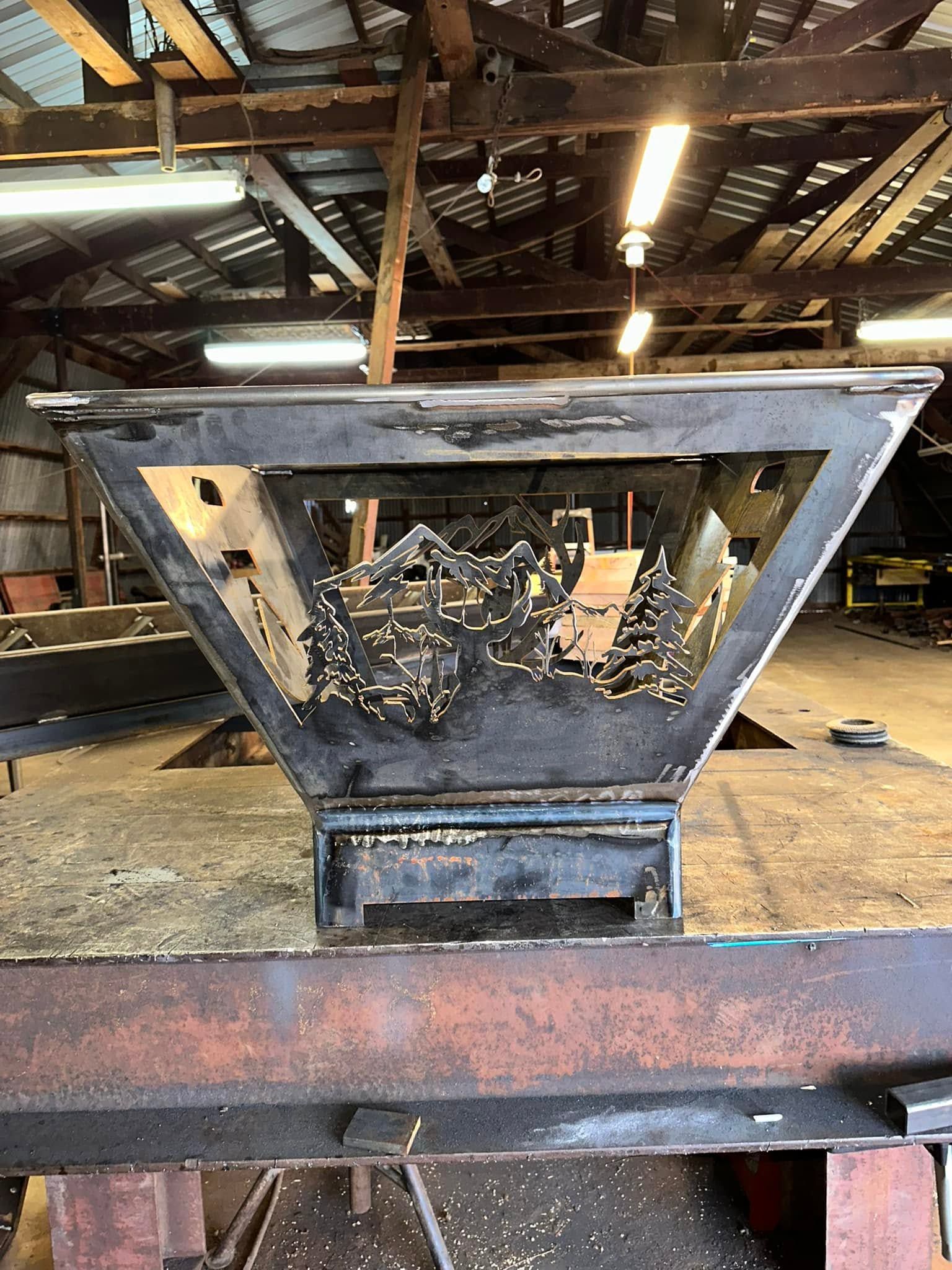 Rusty industrial hopper in a workshop, with metal debris inside and overhead lights above.