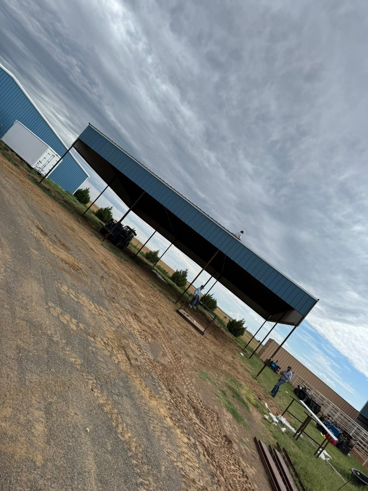 Open gravel lot beside a blue-roofed pavilion under a cloudy sky