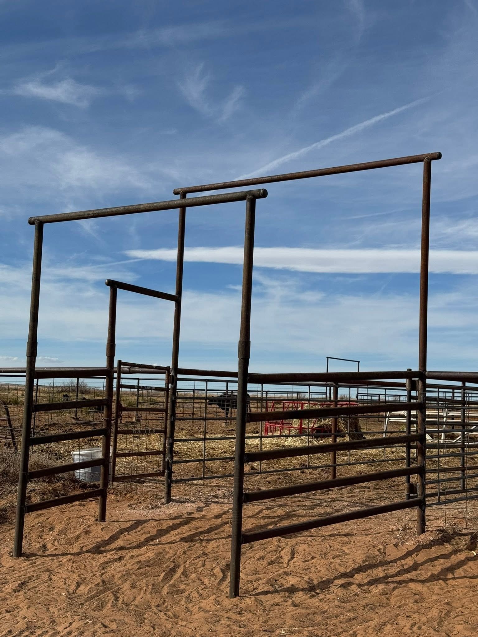 Metal climbing frame on a sandy beach under a blue sky with clouds.
