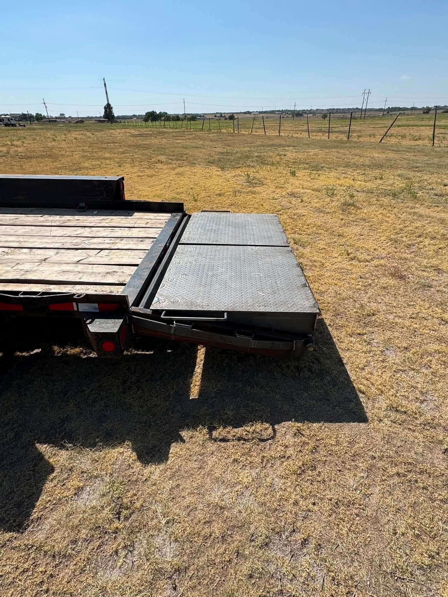 Trailer ramp extending onto a gravel field under a clear sky