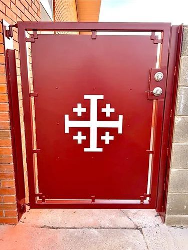 Red metal gate with a white Christian cross emblem