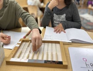 Child using Montessori Flat Bead Frame to explore large-number multiplication through hands-on math.