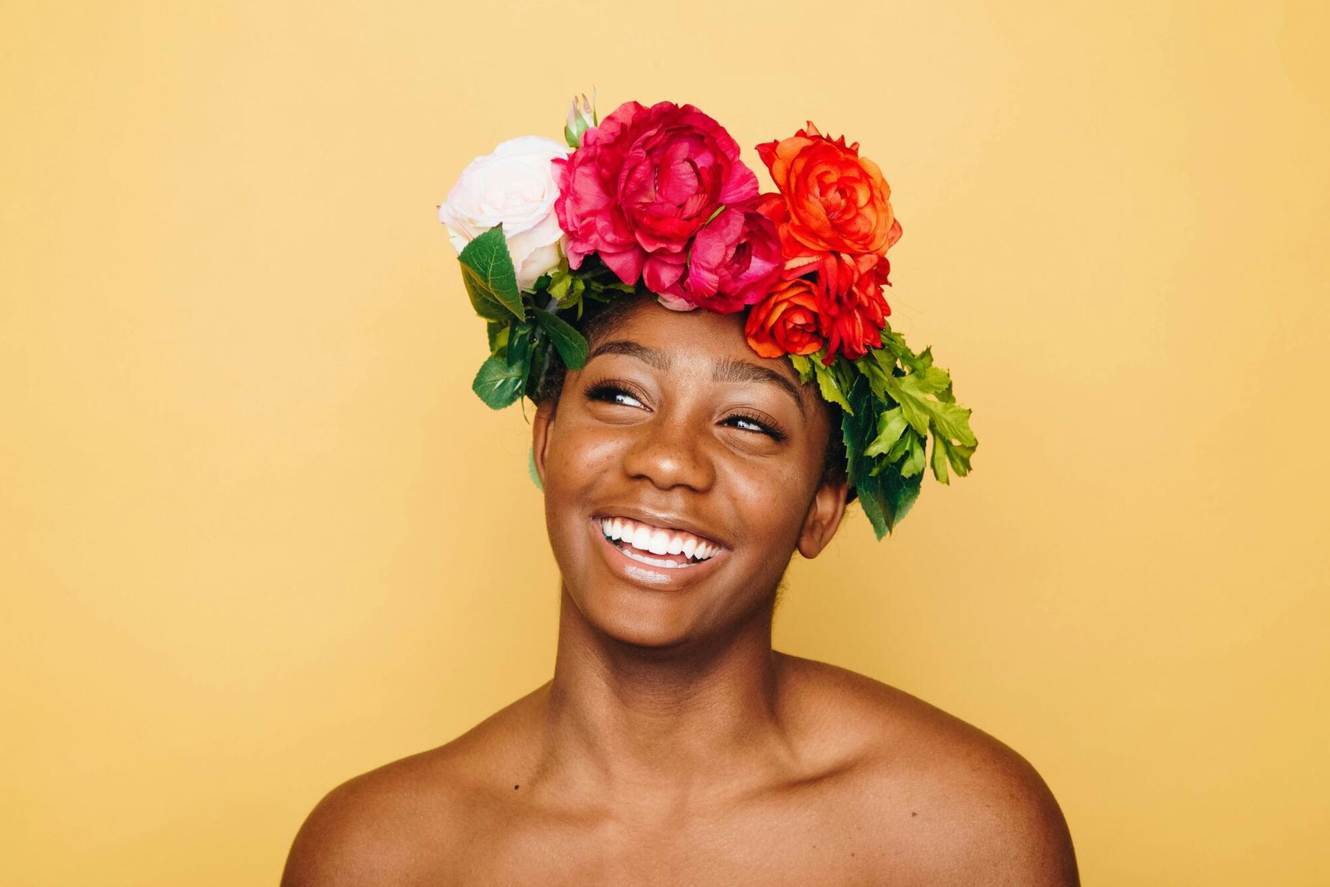 A woman is wearing a flower crown on her head and smiling.