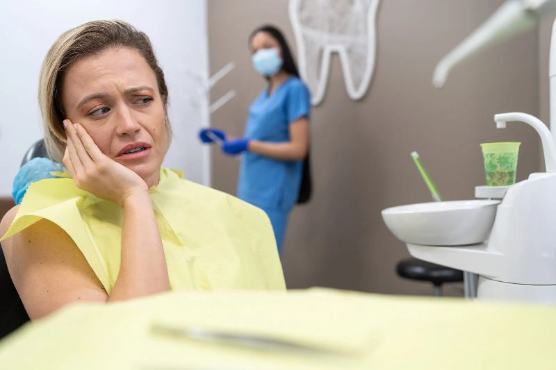 A woman is sitting in a dental chair with a toothache.
