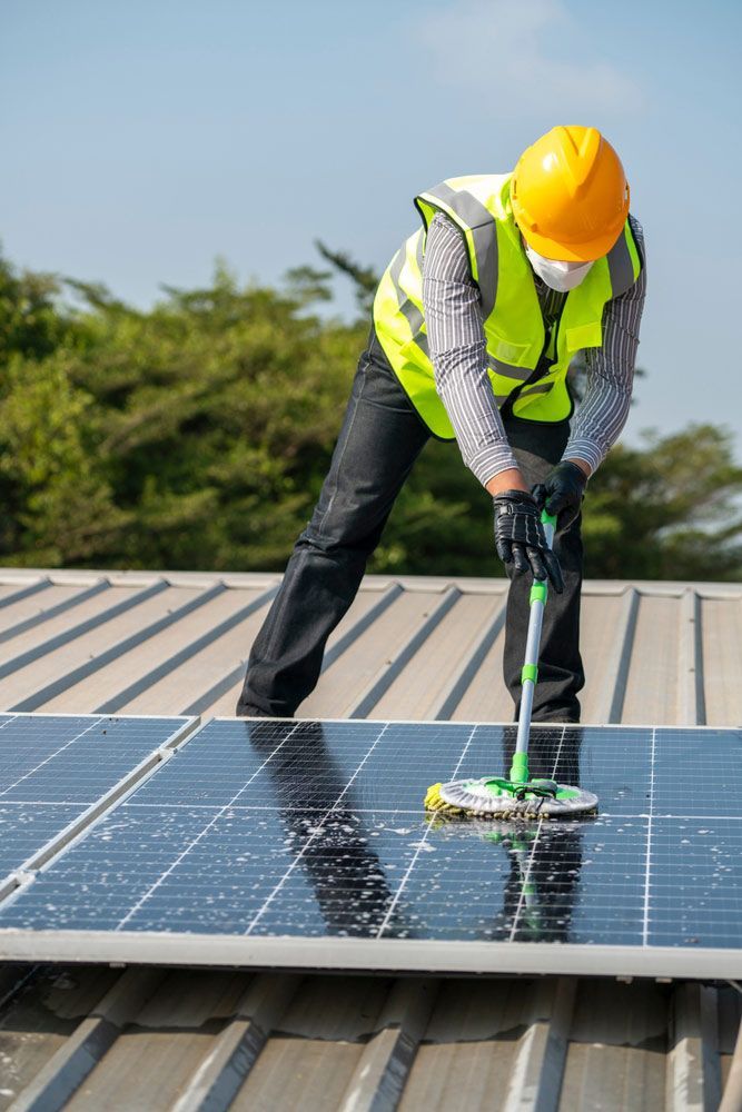 Person Cleaning Solar Panels With a Pressure Washer on a Roof — Cairns Bin Cleaning In Parramatta Park, QLD