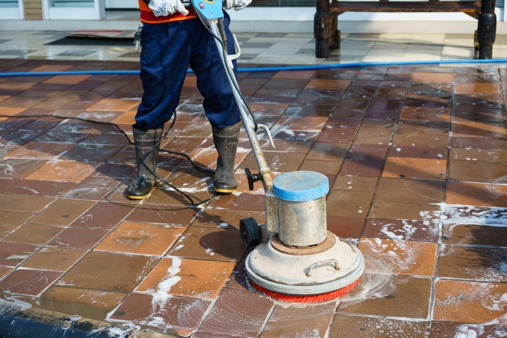 Person Using a Floor Cleaning Machine, Scrubbing a Red-tiled — Cairns Bin Cleaning In Parramatta Park, QLD