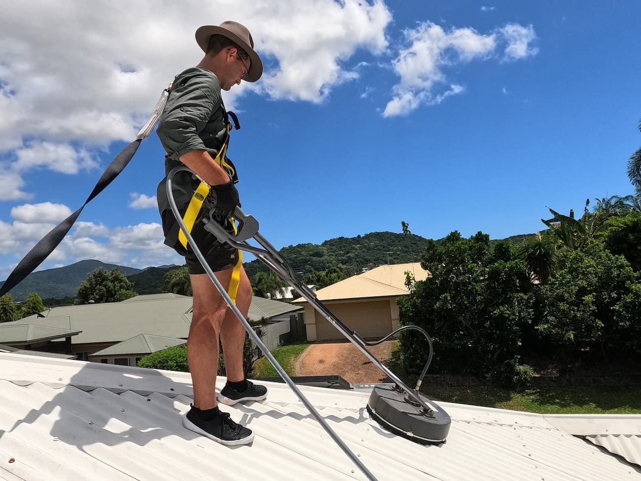 A Man Is Cleaning the Roof of A House with A Vacuum Cleaner — Cairns Bin Cleaning In Parramatta Park, QLD