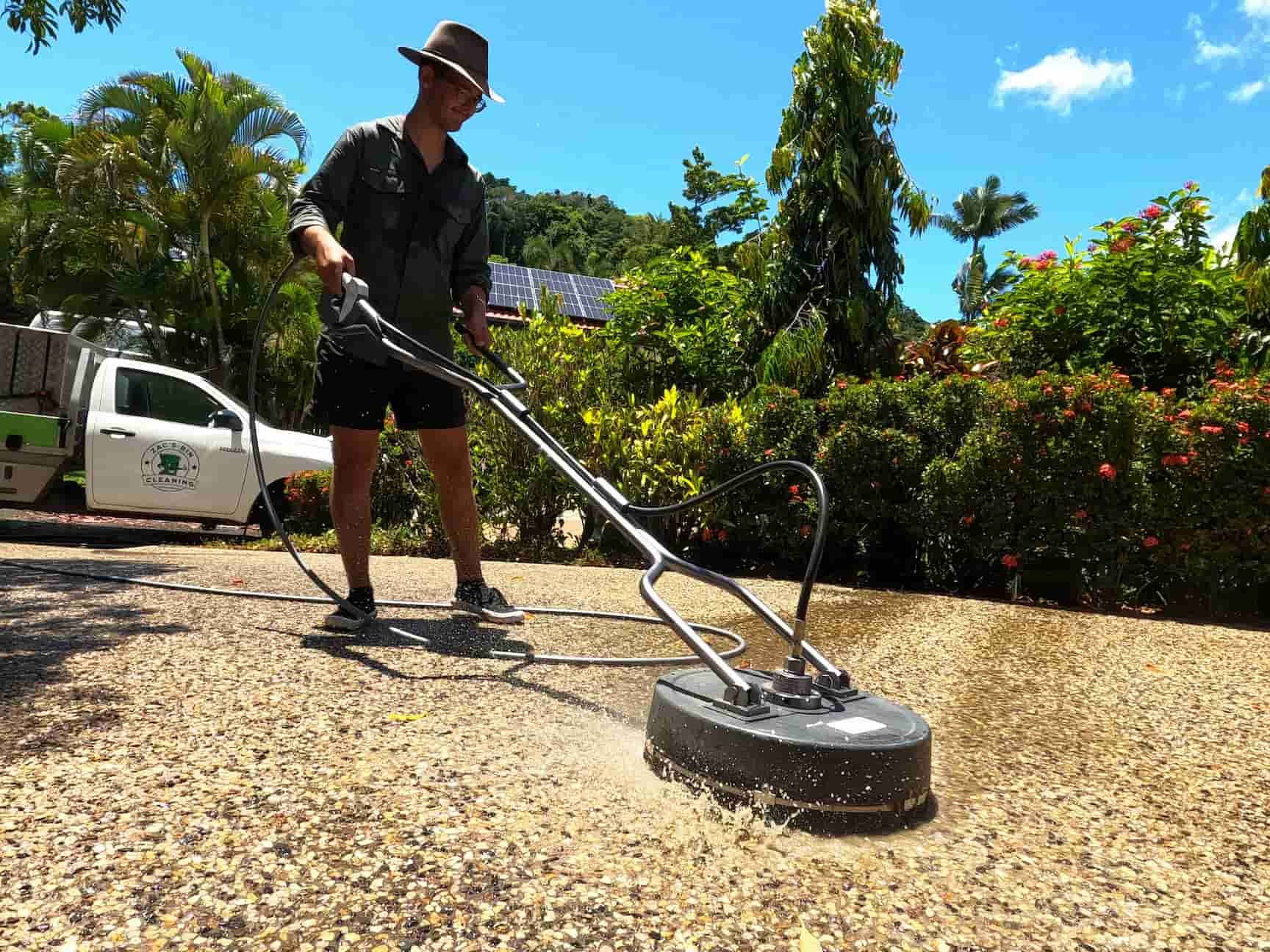A Man Is Using a Machine to Clean a Driveway — Cairns Bin Cleaning In Parramatta Park, QLD