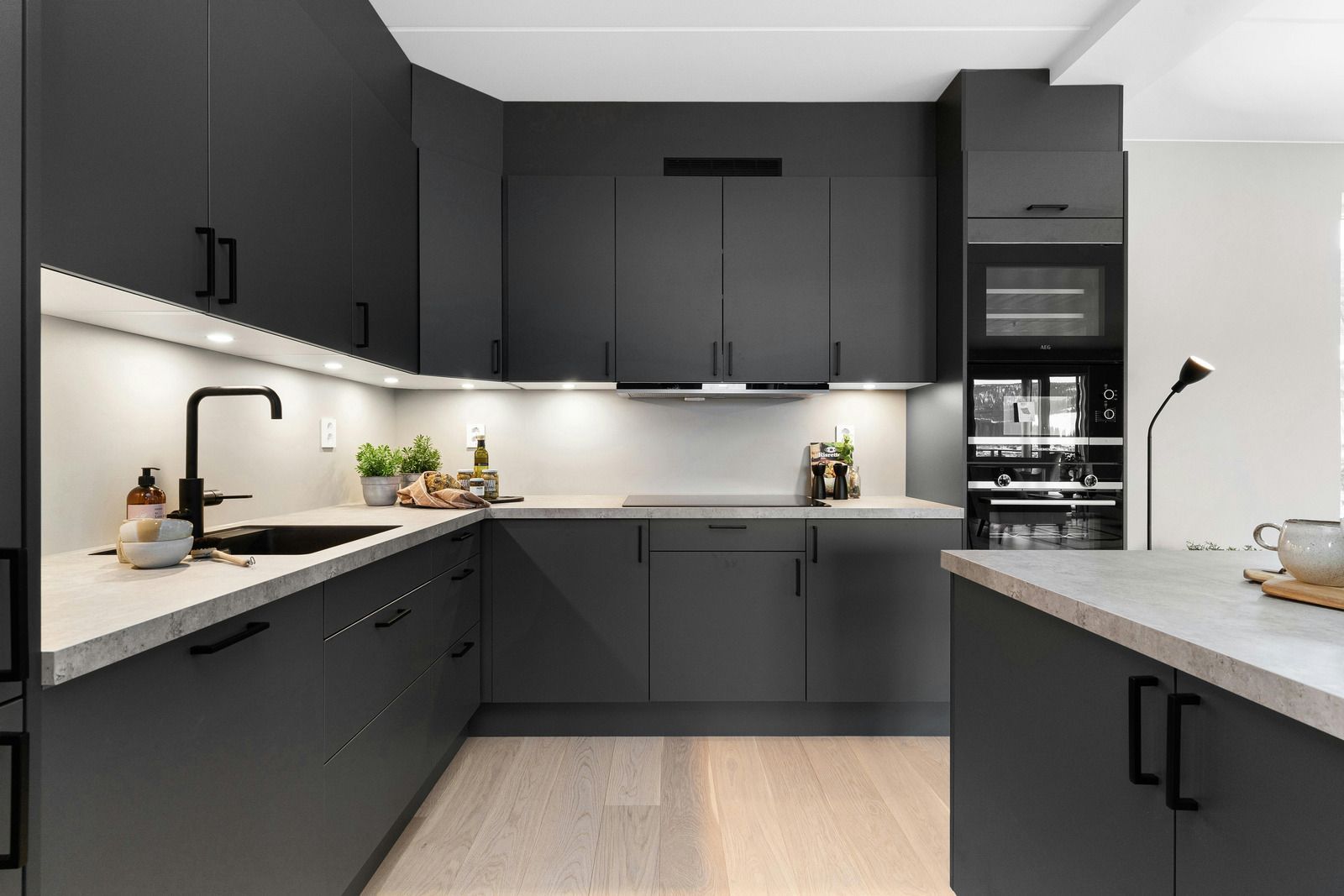 Modern dark-gray kitchen with white countertops, under-cabinet lighting, and built-in appliances