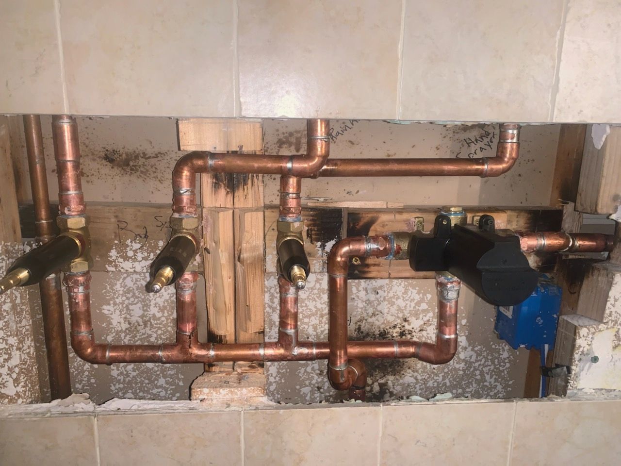 Copper plumbing pipes with shutoff valves inside a wall opening