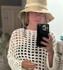 A woman wearing a hat is taking a picture of herself in a mirror.