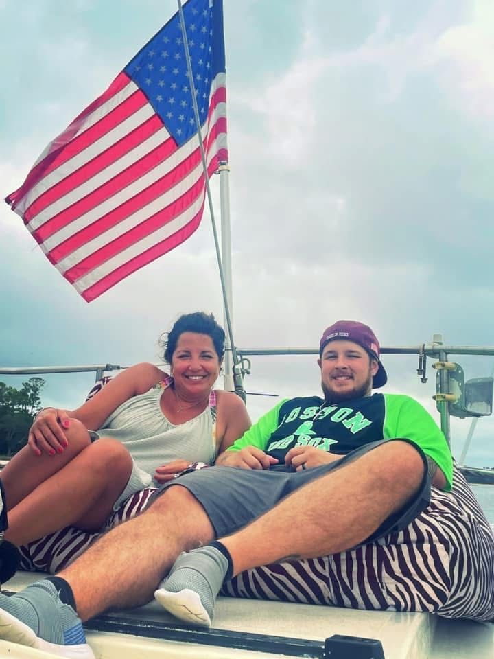 Two people lounging on a boat with an American flag waving overhead.