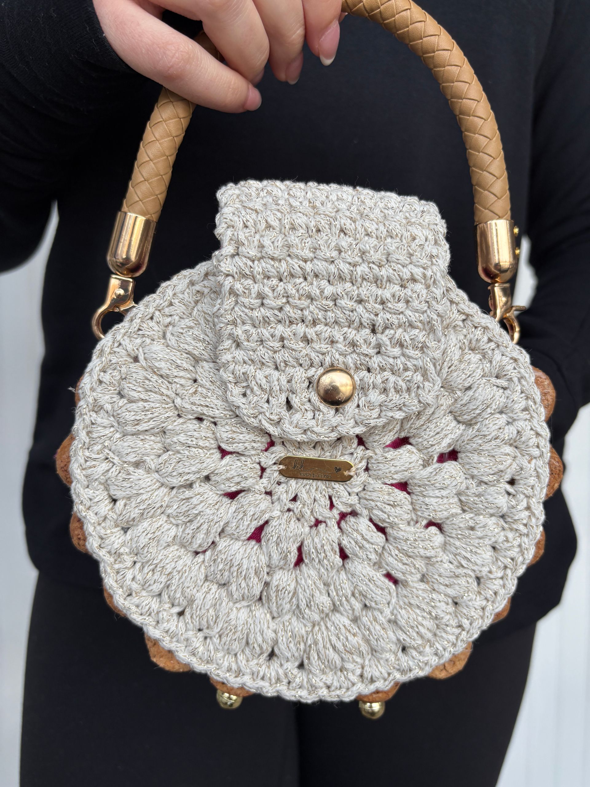 Woman holding a beige crocheted round purse with a cork handle and gold hardware.