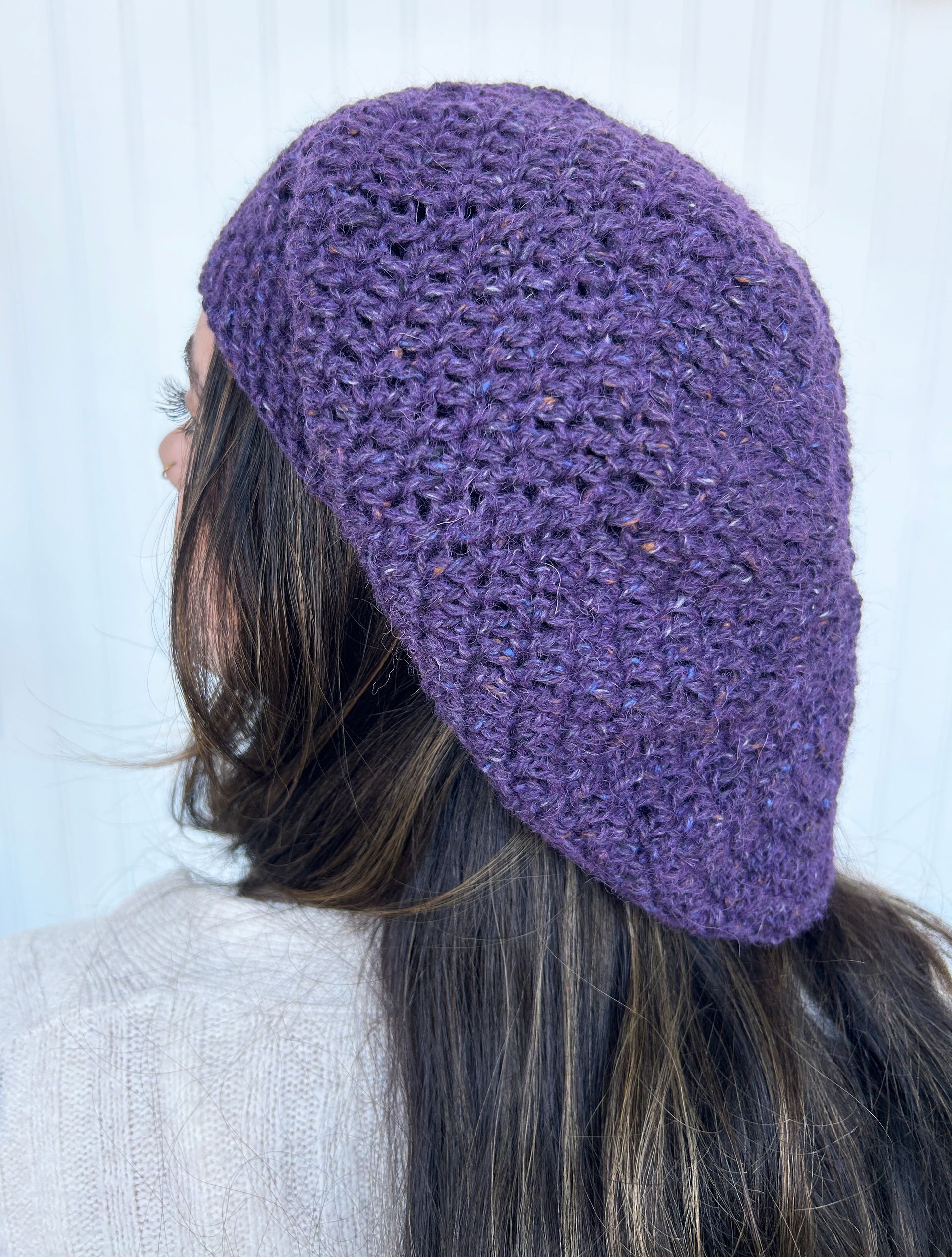 Woman wearing a purple crocheted beret, viewed from the back.