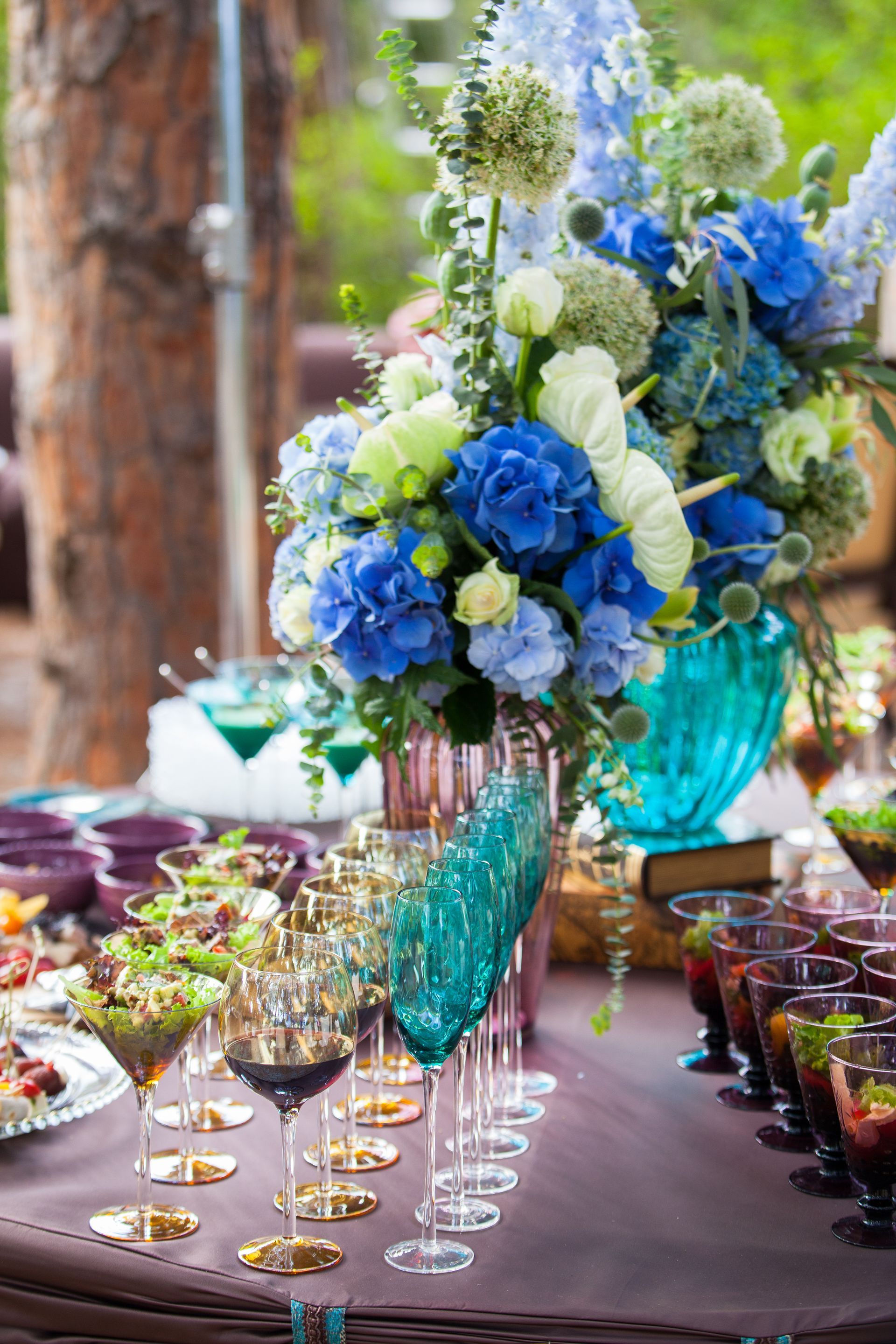 A table with a vase of flowers and wine glasses on it.