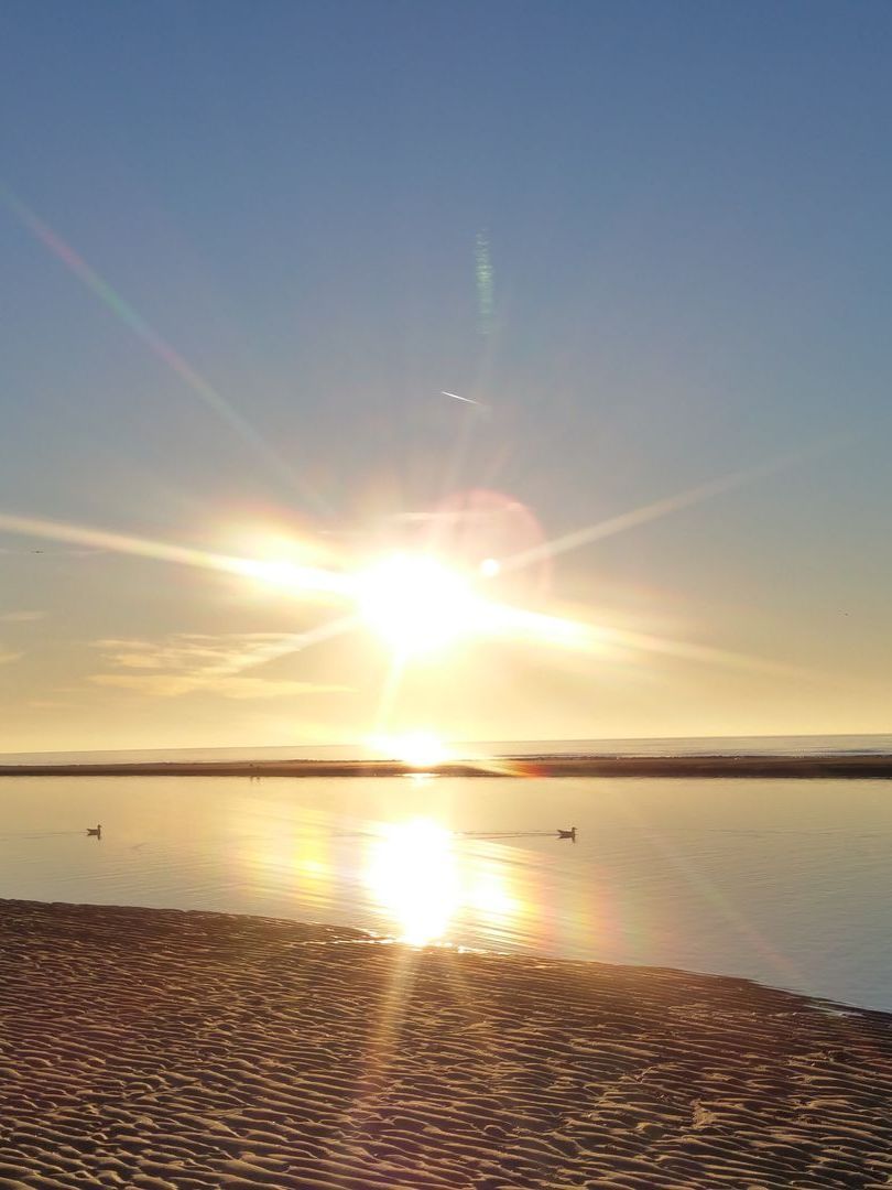 De zon gaat onder boven een watermassa.
