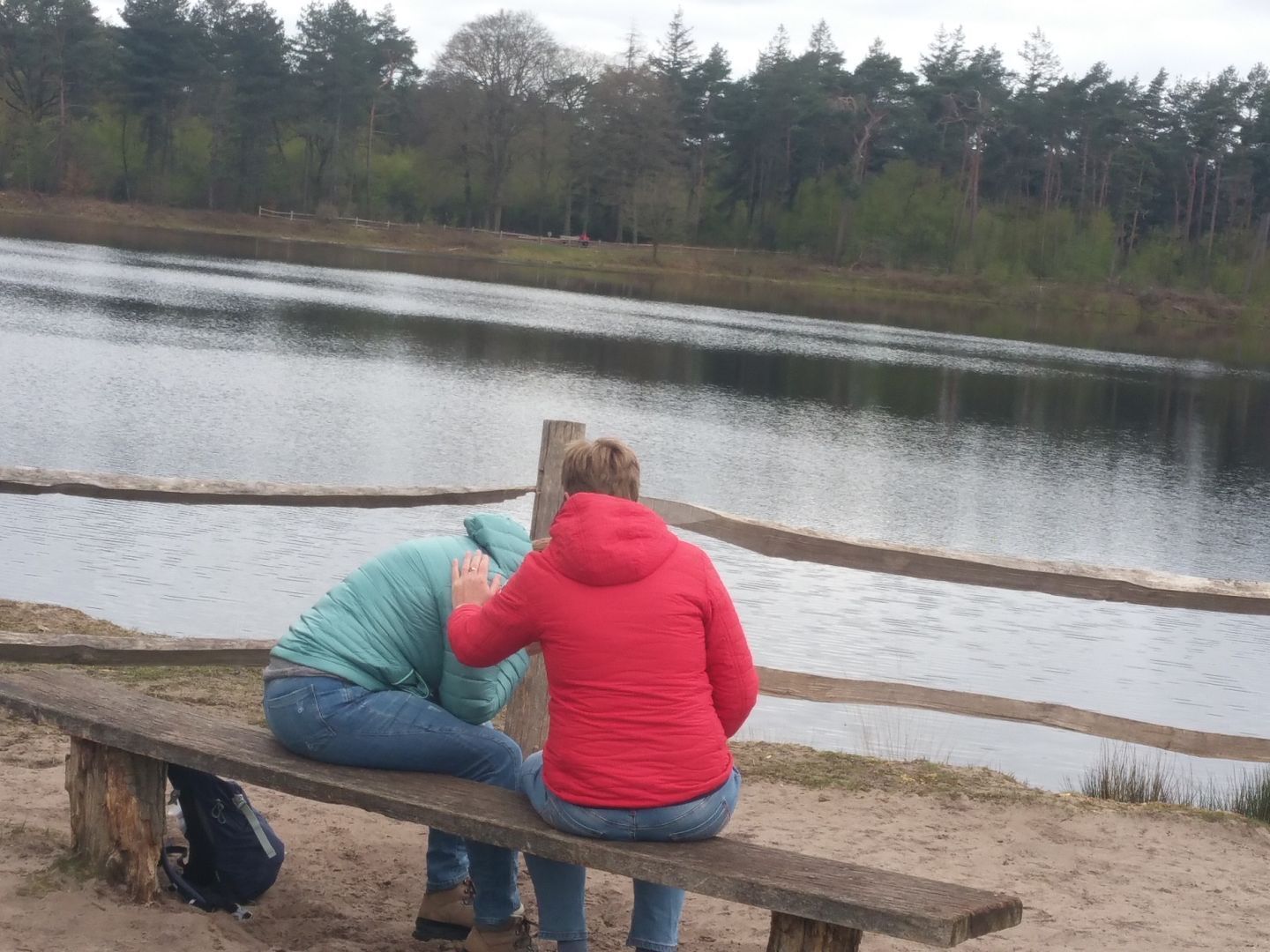 Twee mensen zitten op een bankje bij een meer
