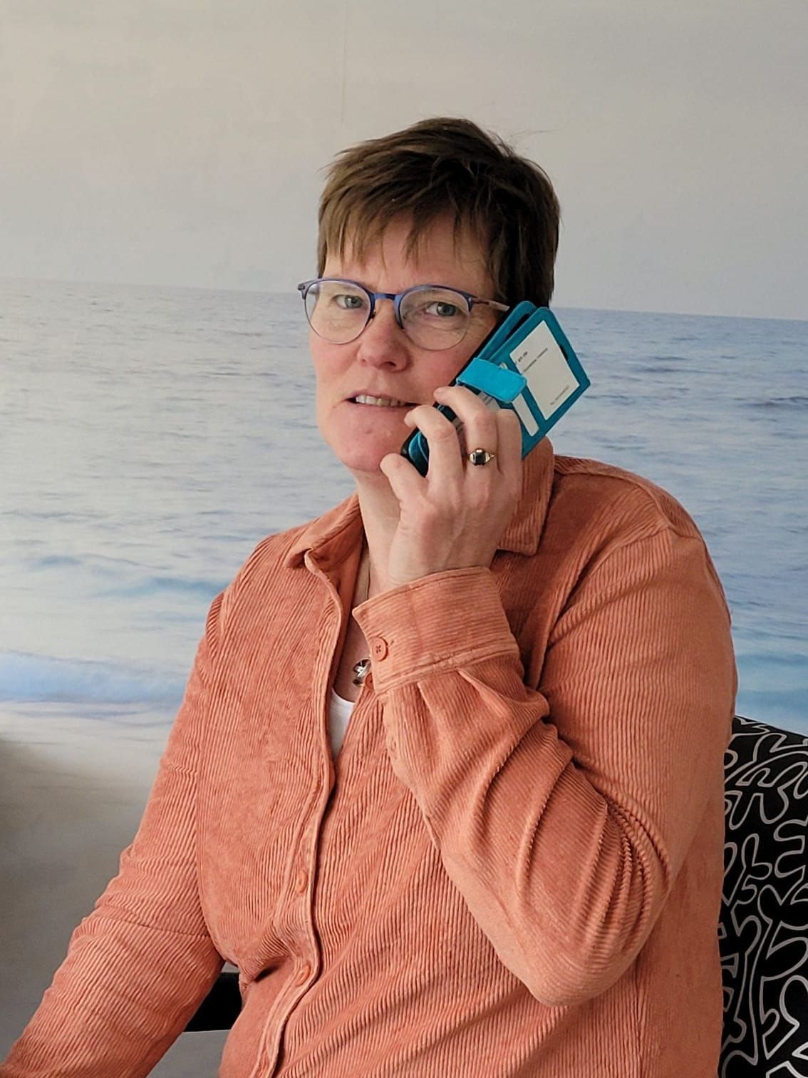 Een vrouw zit op een bank en praat op een mobiele telefoon.