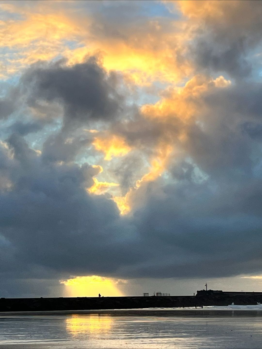 Een zonsondergang boven een watermassa met wolken aan de hemel.
