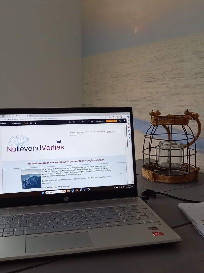 Op een tafel staat een laptop met op de achtergrond een vogelkooi.