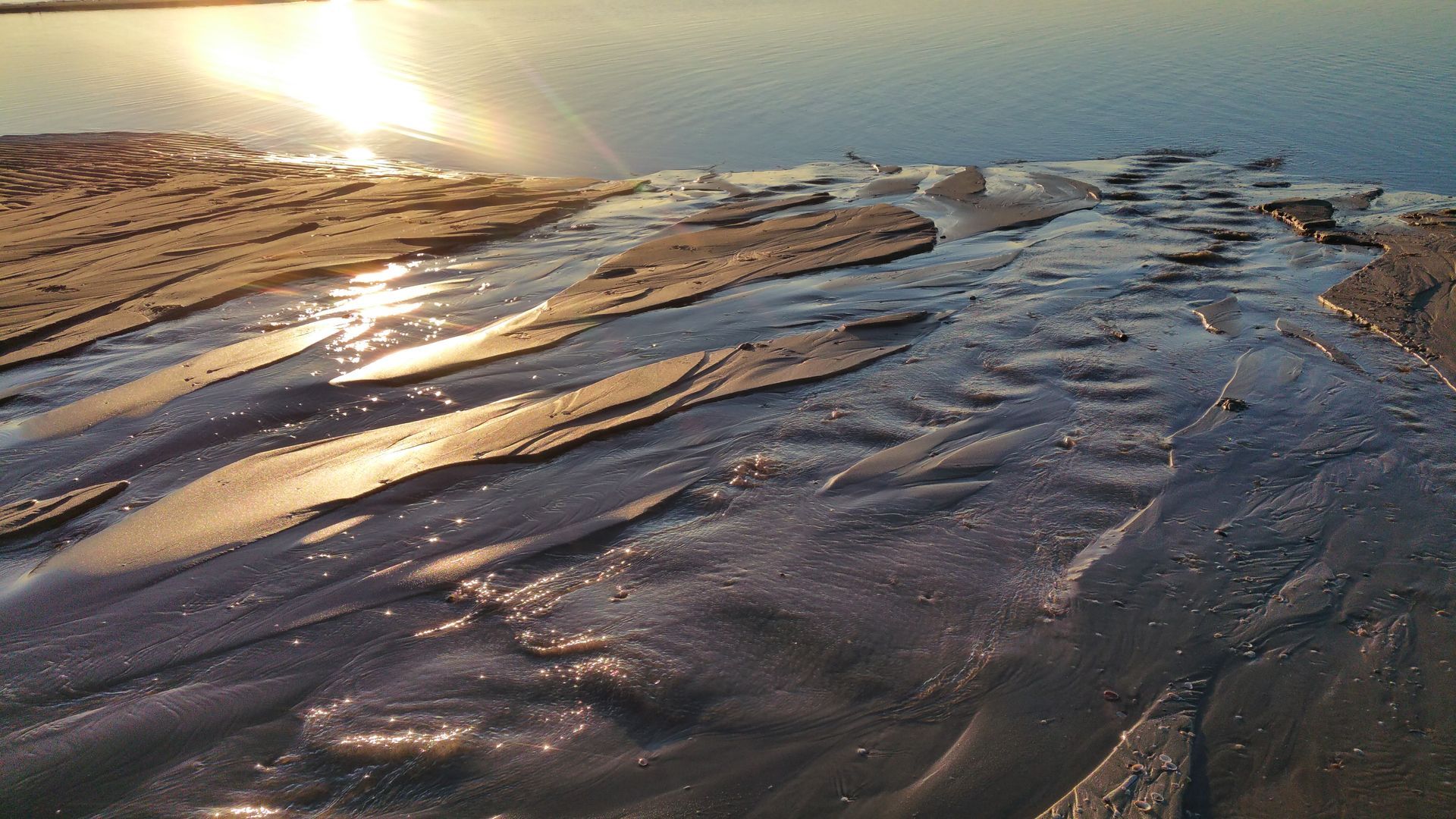 De zon wordt weerspiegeld in het water op het strand