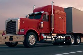 A red semi truck is driving down a highway.
