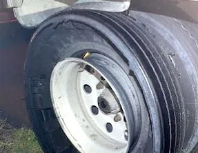 A close up of a truck tire with a hole in it.