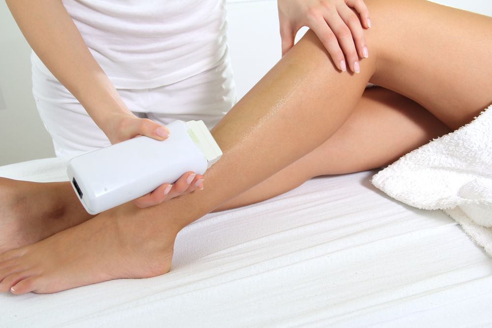 Woman Receiving Leg Wax Treatment in A Spa — Pink Lily Beauty in Blacksmiths, NSW
