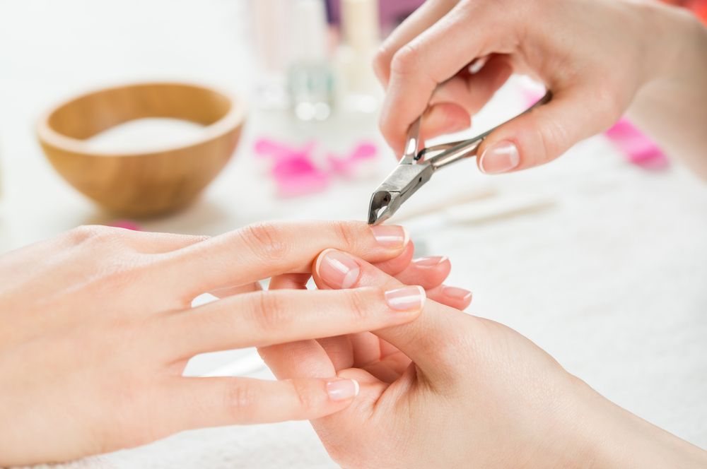 Manicurist Using Nail Clippers on A Client's Fingernails — Pink Lily Beauty in Blacksmiths, NSW